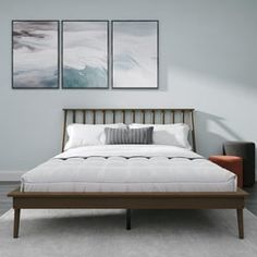 a bed with two paintings on the wall above it