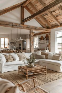 a living room filled with white furniture and wooden beams on the ceiling, along with large windows