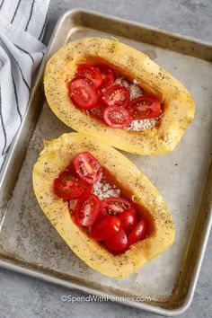 two halves of spaghetti dish stuffed with tomatoes and parmesan cheese on a baking sheet