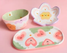 three small dishes on a pink surface one has a flower and the other has hearts