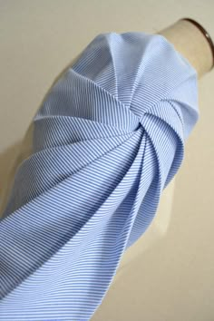 a blue and white striped tie laying on top of a piece of cloth next to a wooden stick