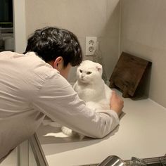 a man holding a white cat on top of a kitchen counter next to a stove