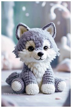 a gray and white stuffed animal sitting on top of a bed