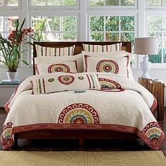 a bed in a room with lots of windows and pillows on the bed, along with a vase full of flowers