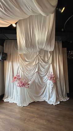 a room with white drapes and flowers on the floor