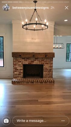 an empty living room with a fireplace and chandelier in the middle of it