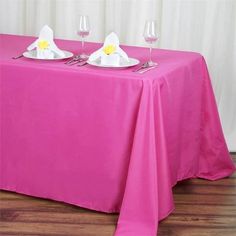 the table is covered with pink cloths and place settings for two people to sit at