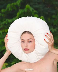 a shirtless woman holding a large pillow over her head