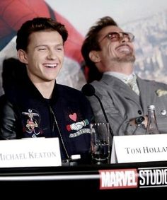 two men sitting next to each other in front of microphones at a press conference