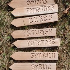 wooden signs pointing in different directions on the grass