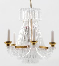 a glass chandelier with three candles hanging from it's center and two arms