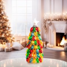 a christmas tree made out of candy sits on a table in front of a fireplace