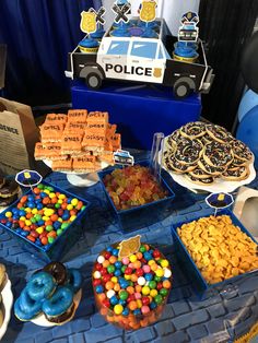 a table topped with lots of desserts next to a police cake and cupcake