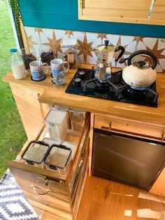 a stove top oven sitting inside of a kitchen next to a wooden counter with pots and pans on it