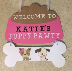 a welcome sign with two dogs hanging from it's sides and the words, welcome to kate's puppy pawty