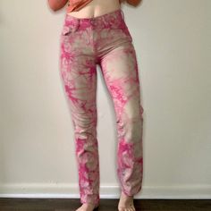 a woman standing in front of a white wall wearing pink tie dye pants and an orange tank top