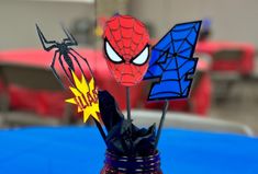 a spiderman centerpiece in a mason jar on a blue tablecloth with red chairs