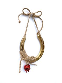 a gold necklace with a red heart hanging from it's side on a white background