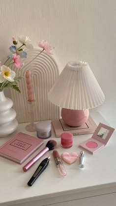 a white table topped with pink items and a vase filled with flowers on top of it