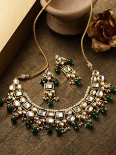 This impressive jewelry set consists of a kundan studded necklace and a pair of matching drop earrings. The beautiful necklace shown in green comes gold-plated with kundan stone studs and green & white accent beads, and secured with an adjustable drawstring closure. A pair of matching drop earrings come secured with a post and back closure. This statement piece can add impact to any outfit for any festive occasion! Product color may vary based on the monitor or screen you are using.See FAQ for m Green Kundan Emerald Necklace For Gift, Green Kundan Necklaces With Latkans, Green Kundan Jewelry Sets As Gift, Green Kundan Jewelry Sets For Gifts, Green Kundan Beaded Necklace Gift, Green Kundan Jeweled Bridal Necklace, Bollywood Style Green Jeweled Necklaces, Green Temple Jewelry Sets, Jeweled, Green Jeweled Temple Jewelry Sets