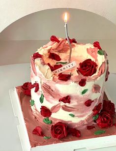 a birthday cake with roses and a single candle