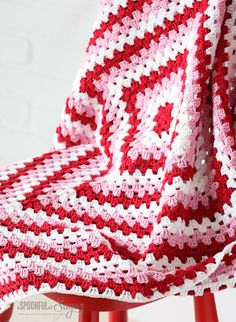 a red and white crocheted blanket sitting on top of a chair