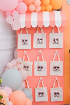 there is a pink and white wall with many bags hanging from it's sides