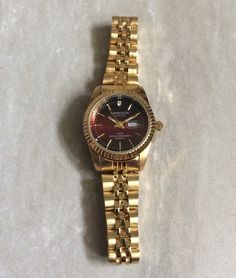 Swanson gold women's watch, having a round red dial displaying gold index hour markers and a date indicator at the third hour position, all on a gold stainless steel linked band! this is a beautiful watch still brand new unused vintage watch, ready to be cherished & enjoyed! this item will arrive in perfect working condtion, inside a velvet watch pouch, perfect for gifting! water resistant 5atm rated. measurements: bezel/case 1 1/4" x 1", dial diameter 3/4", band width 1/2" and fits a standard 7.5" wrist perfectly. however, if a smaller perfect fit is needed, we offer free sizing. just contact us prior to purchasing this item, for details needed for the custom sizing process. we ship fast, the next business day, for a quick delivery to you! may you have a wonderful time shopping, best wish Red Watch With Date Indicator And Round Dial, Gold Round Watches With Date Display, Classic Red Watch With Metal Dial, Classic Red Watch Accessories With Date Indicator, Classic Red Watches With Date Display, Red Analog Watch For Formal Occasions, Classic Red Round Watch, Formal Red Analog Watch, Red Formal Watch With Date Indicator