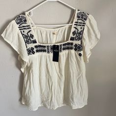 Hollister Embroidered White Ruffle Top Embroidery Print Nwt Size Xs New With Tag. 51% Cotton 49% Viscose. Hollister Tank Tops, Top Embroidery, White Ruffle Top, Black And White Flannel, Embroidery Print, Cold Shoulder Shirt, Long Sleeve Wrap Top, Half Zip Hoodie, Hollister Sweater