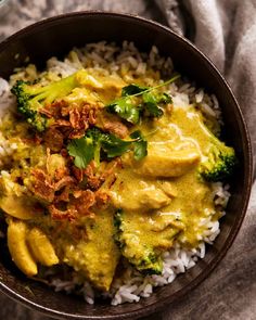 a bowl filled with rice and broccoli covered in yellow sauce on top of a table