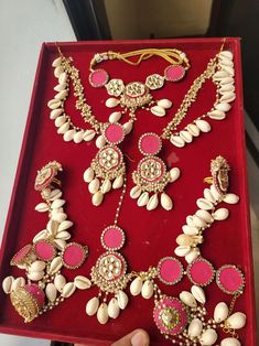 a red tray with some white and pink jewelry on it