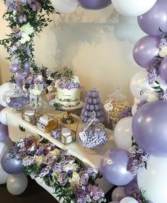 a dessert table with purple and white balloons