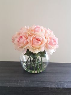 a vase filled with pink roses on top of a wooden table