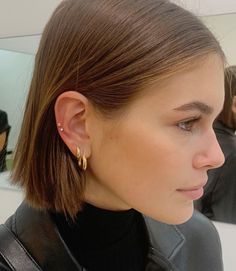 a woman in a black jacket is looking at her cell phone and wearing earrings