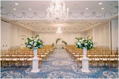 a room filled with lots of chairs covered in white and blue floral centerpieces