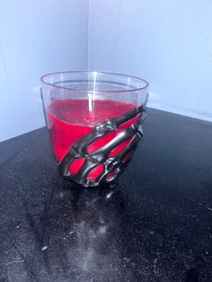 a glass with red liquid and black scissors in it