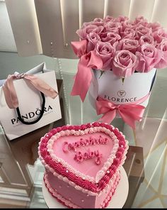 a heart shaped cake sitting on top of a table next to a bouquet of roses