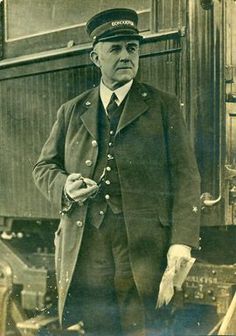 an old black and white photo of a man in uniform standing next to a train