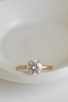 a white plate with a gold ring on it and a single diamond in the middle