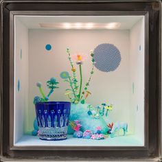 a blue vase sitting on top of a shelf filled with flowers and other things in it