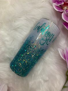 a blue and green glitter tumbler sitting on top of a white fur covered floor