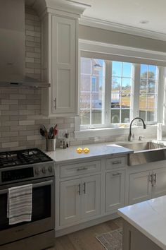 a kitchen with an oven, sink and stove top in front of a large window