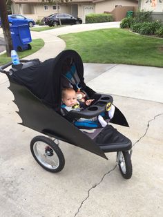 a baby in a stroller with a batman cape on it's head and mouth