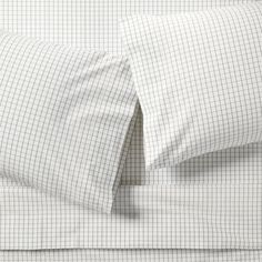 a bed with two pillows on top of it next to a pillow case and sheets