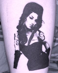 a black and white photo of a woman's arm with tattoos on her legs