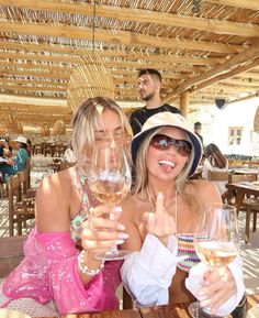 two women sitting at a table holding wine glasses