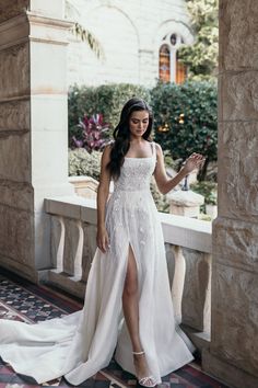 a woman in a white dress is standing on a balcony and posing for the camera