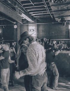 black and white photograph of people dancing in an old fashioned room with exposed ceilinging