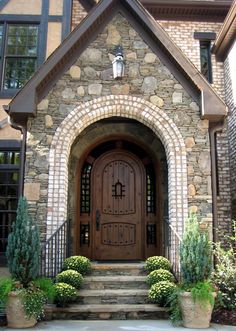 the front entrance to a large home with stone steps and potted plants on either side