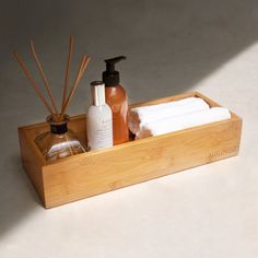 bamboo tray with soaps, lotion and other items in it on a white surface